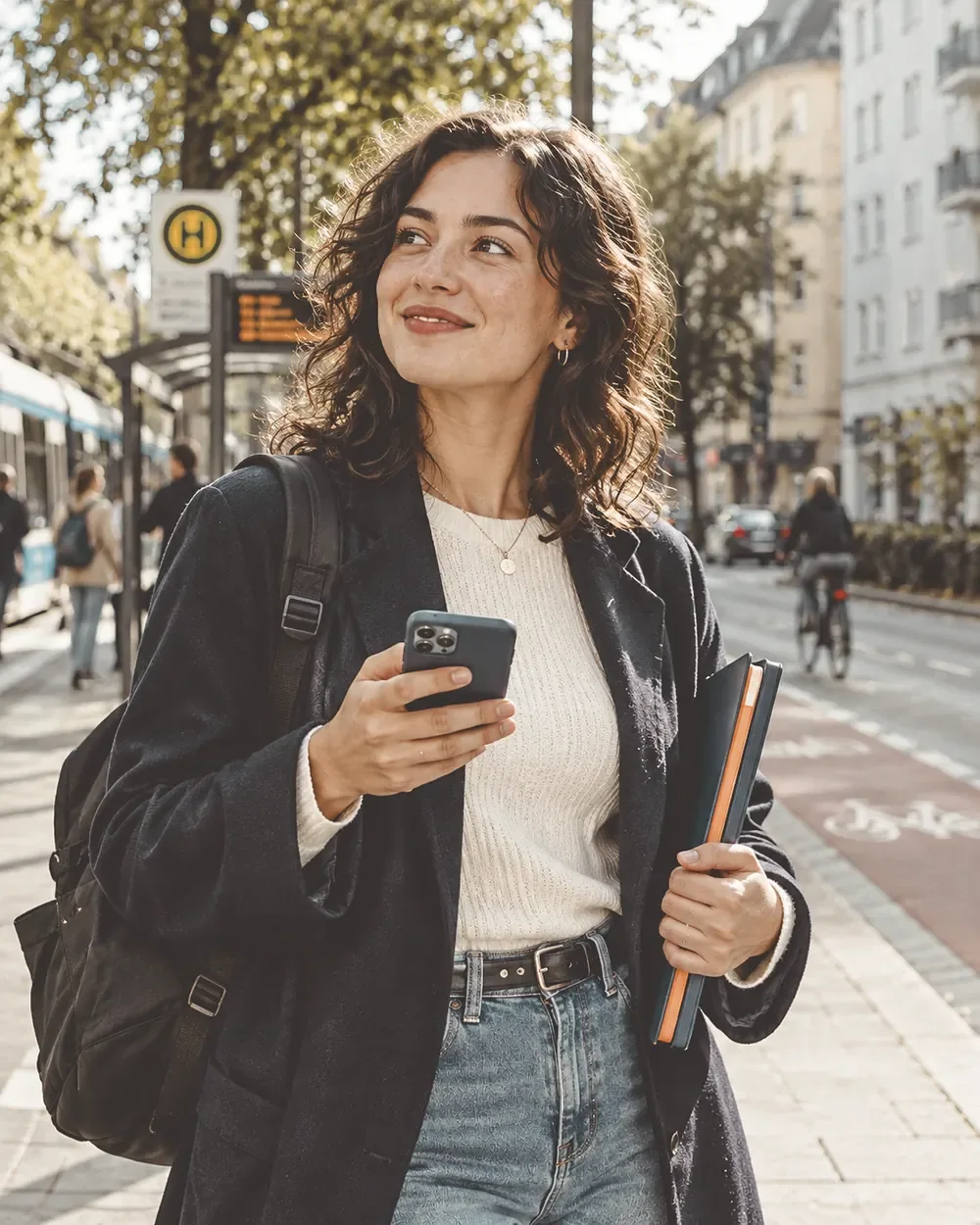 Eine Frau mit Smartphone an einer Haltestelle.
